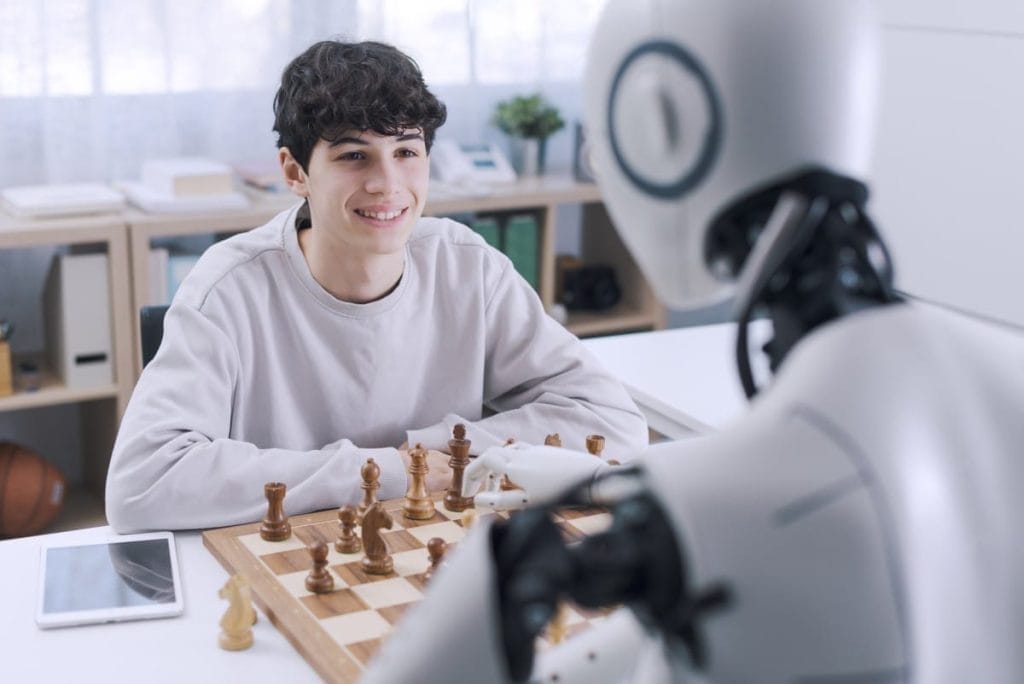 A teenager playing chess with a robot in a modern office, showcasing human-AI interaction