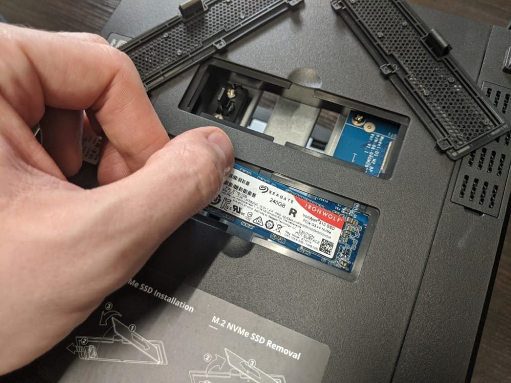 A person is installing a Seagate IronWolf SSD into Synology NAS, showcasing M.2 NVMe SSD installation.