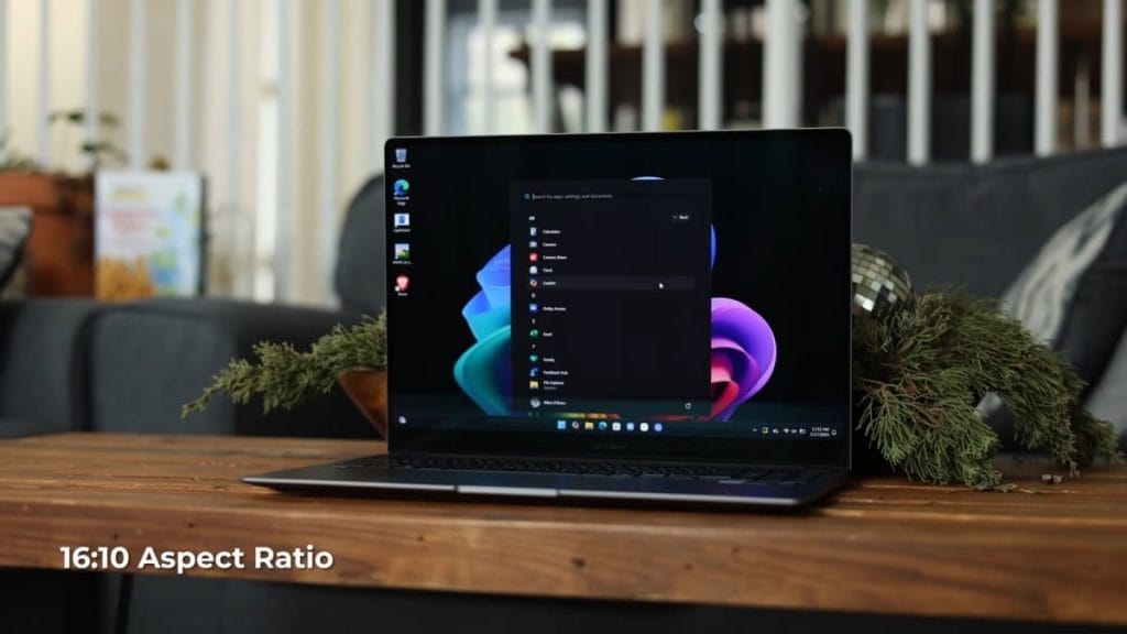 Samsung Galaxy Book 5 Pro with Windows 11, displaying the app menu and settings, featuring a 16:10 aspect ratio on a wooden table.