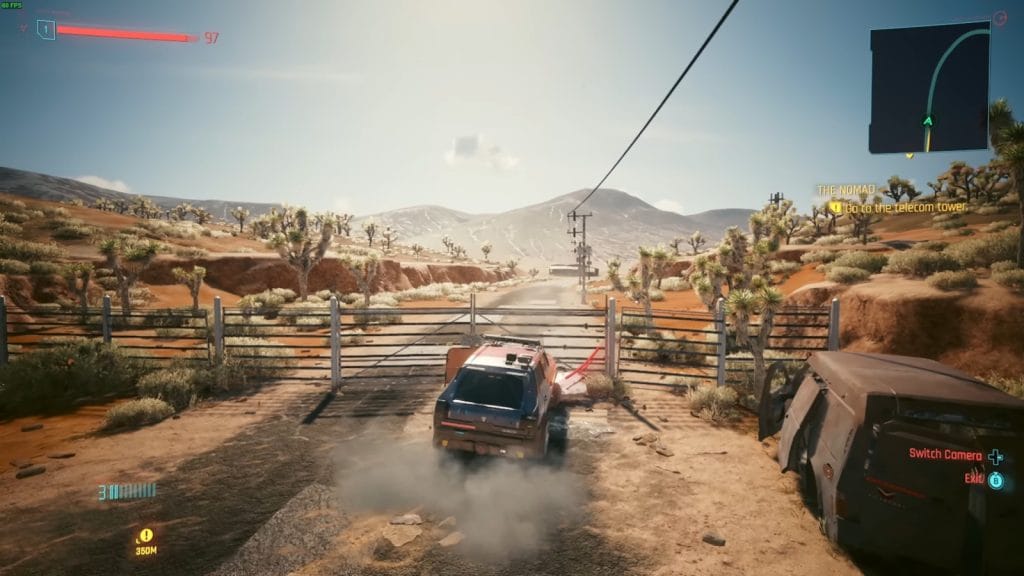 A car navigating through a desert landscape in a video game with a clear sky and distant mountains.