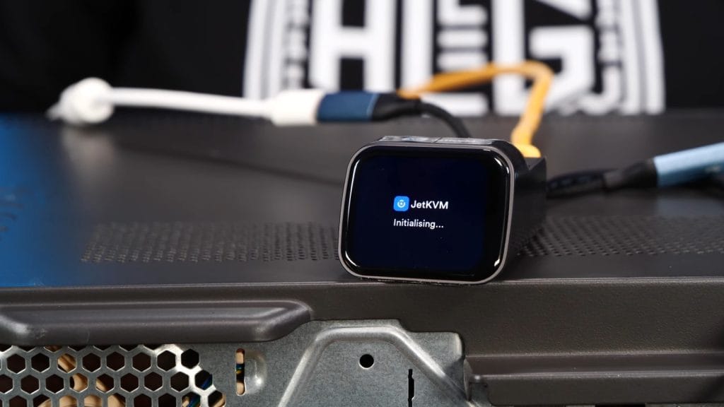 A JetKVM device displaying 'Initialising...' on its screen, connected to a server.