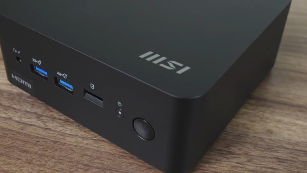 A close-up view of an MSI mini PC showing its USB ports and HDMI output on a wooden surface.