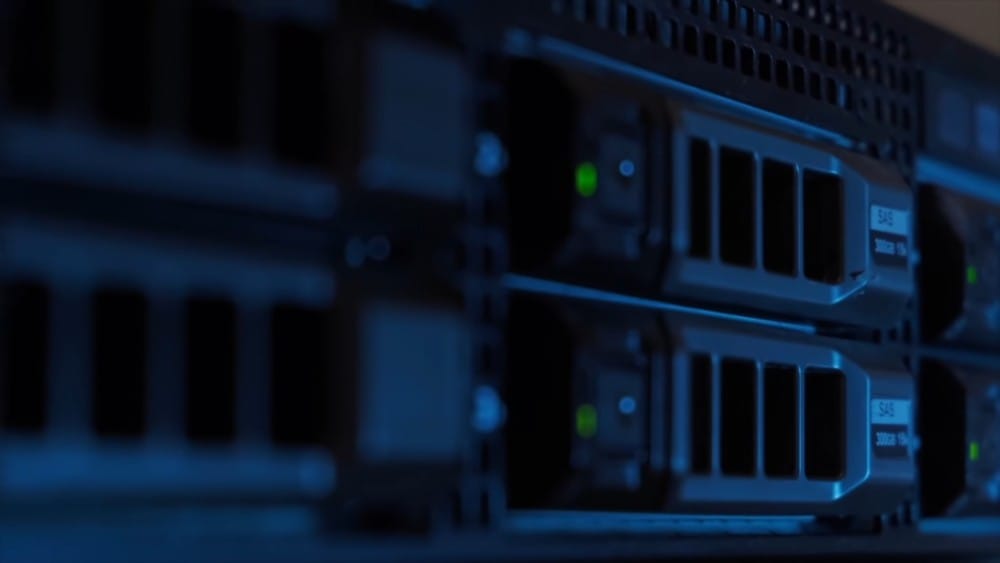 A close-up view of server drives in a data center with blue lighting, showcasing advanced technology.