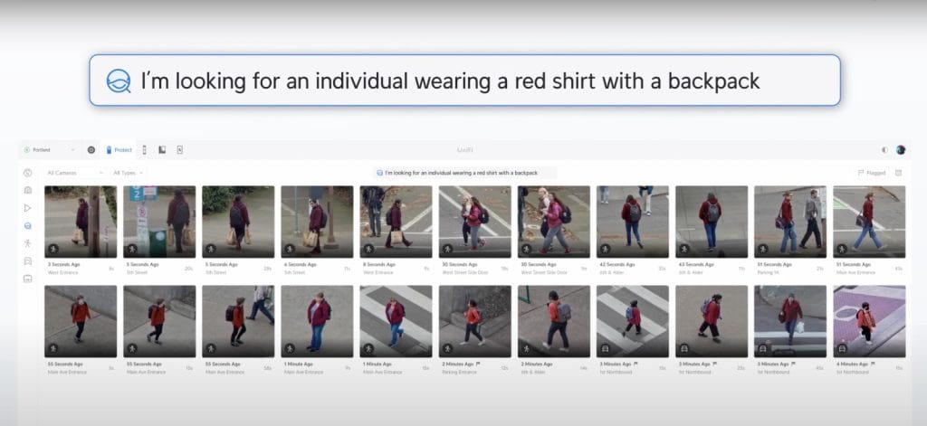 A surveillance capture of individuals walking in a city, including one wearing a red shirt and a backpack.