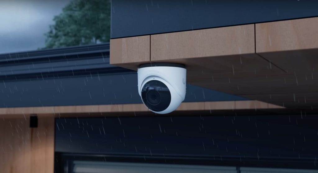 A high-definition security camera mounted under an eave, capturing images in rainy weather.