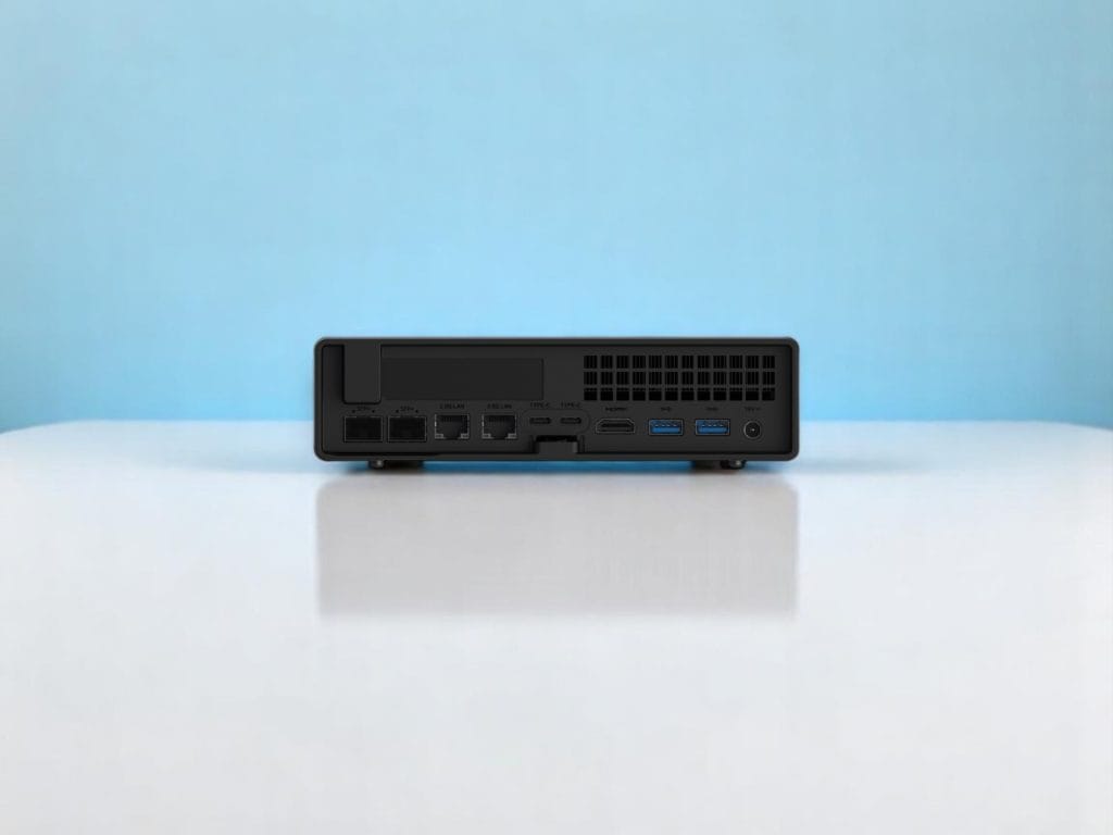Minisforum MS-A2. Back view of a compact black mini PC with multiple ports including USB, LAN, SFP+, HDMI, and power input on a glossy white surface with a blue background
