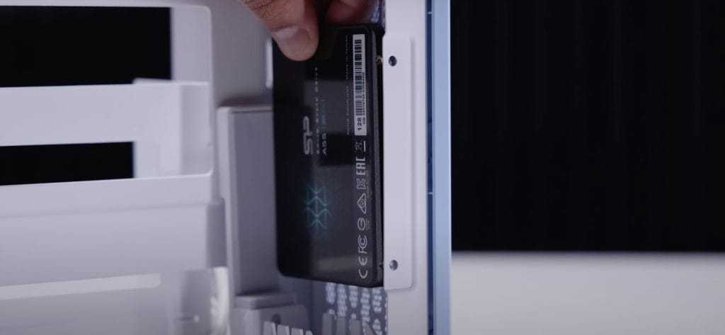 Thermaltake TR100 SFF A close-up view of an SSD being installed into a computer case, showcasing hardware setup for improved performance.