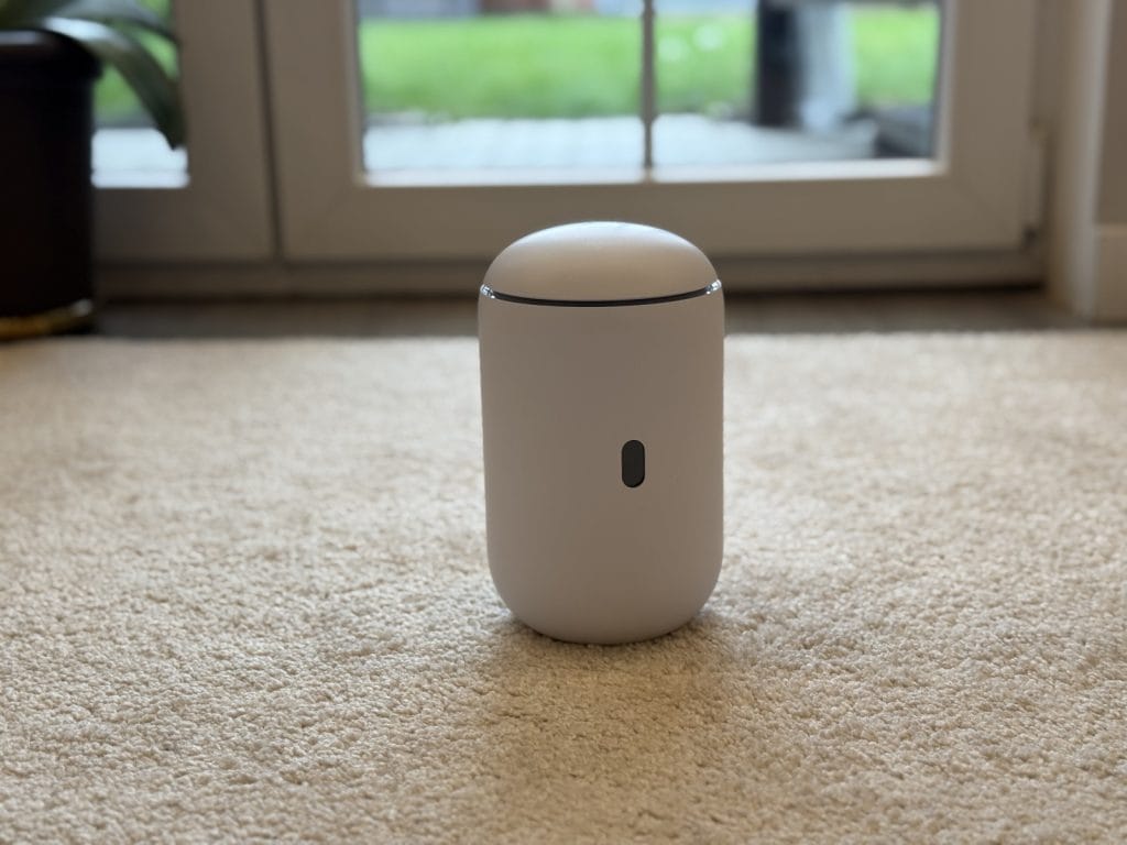 UniFi Dream Router 7. Modern, sleek white air purifier placed on a beige carpet in front of glass doors