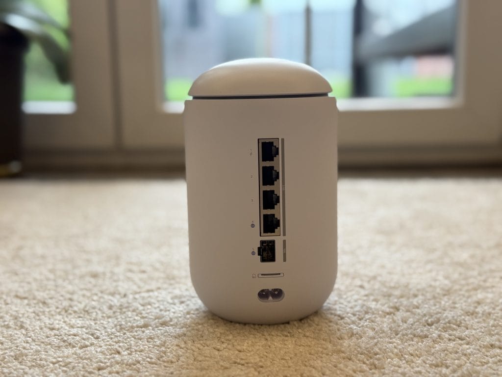 UniFi Dream Router 7. White wireless router with multiple Ethernet ports on a beige carpet