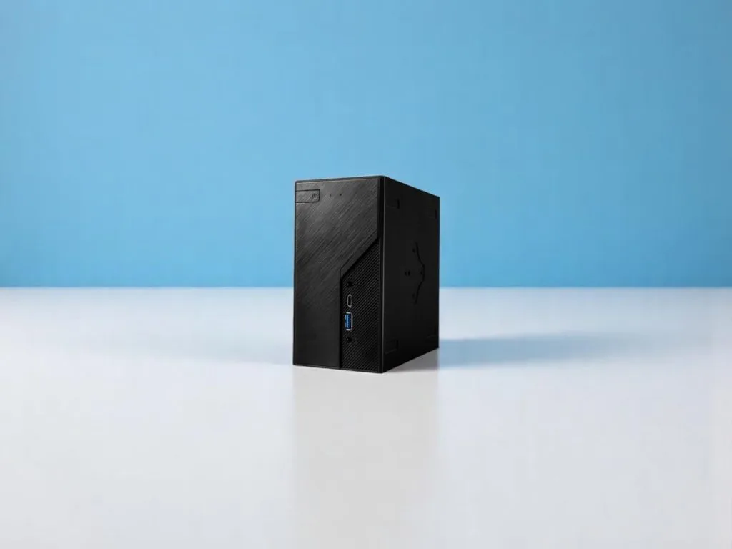 ASRock DeskMini X600. A compact black mini PC with USB ports placed on a white surface and a blue background