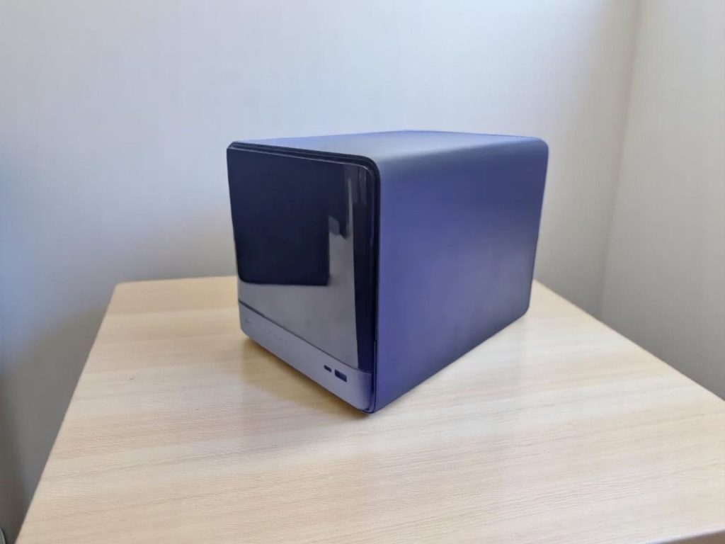 Minisforum N5 Pro NAS. A sleek black and blue network attached storage device on a wooden table