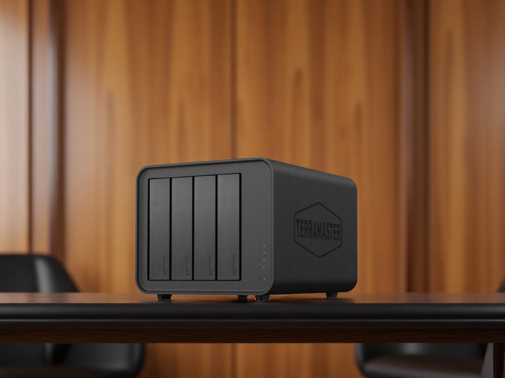 A black TerraMaster 4-bay external hard drive or NAS device on a wooden table with a blurred wood panel background